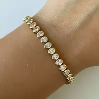 oval shaped diamond tennis bracelet on a hand in yellow gold