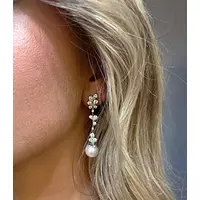 flower design diamond and pearl earrings for rent on a model
